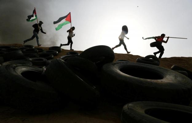 Palestinian protesters run during clashes with Israeli troops at Israel-Gaza border, in the southern Gaza Strip